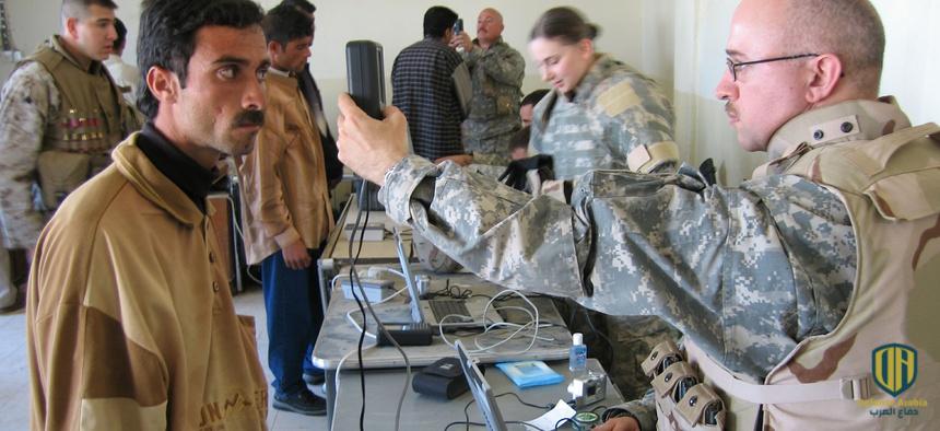 جندي أمريكي يُجري مسحًا لقزحية العين لرجل عراقي أثناء حملة تجنيد للجيش العراقي في مدينة الرمادي (أسوشيتد برس)